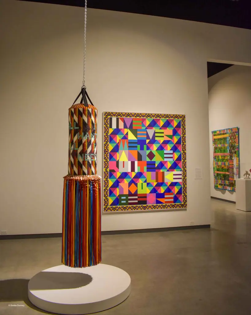 Colorful textile punching bag and geometric artwork displayed in a museum